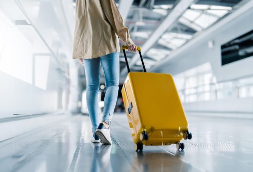 Woman with luggage walking in airport - How to travel safely with your money